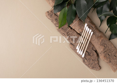 Wood cotton swabs on natural bark, green leaves 136451370