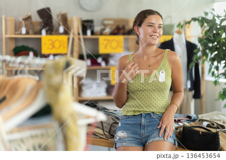 Positive joyful woman looking for fashionable clothes in clothing boutique 136453654