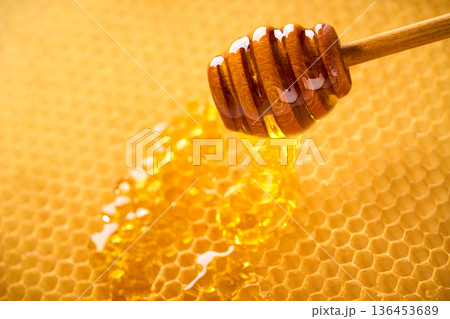 Macro shot of natural honey drop dripping from the honeycomb. 136453689
