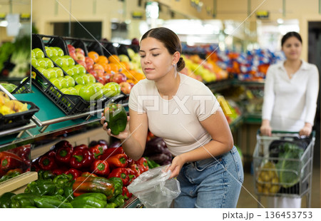 Young woman shopper chooses bell pepper in supermarket Young woman shopper chooses bell pepper in supermarket 136453753
