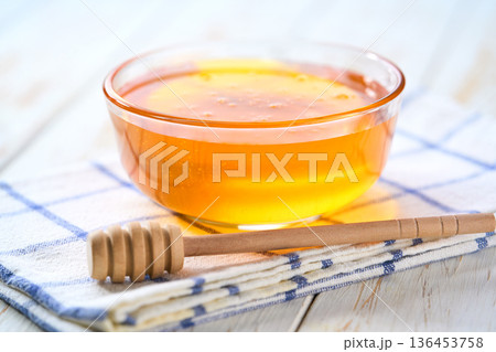 Glass bowl with sweet honey on white table, selective focus. Glass bowl with sweet honey on white table, selective focus. 136453758