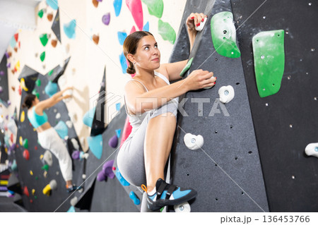 Young woman practicing rock climbing on climbing wall 136453766