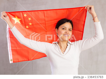 Joyful female fan of the favorite team of China with national flag in her hands 136453783