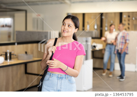 Young Asian female shopper browsing bathroom fixtures in showroom Young Asian female shopper browsing bathroom fixtures in showroom 136453795
