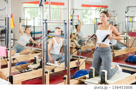 Young girl doing arm exercises on cable reformer device 136453806