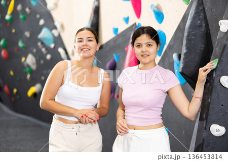 .Women are standing in gym and discussing possible options for overcoming difficult climbing route .Women are standing in gym and discussing possible options for overcoming difficult climbing route 136453814