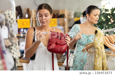 Happy young woman choosing handbag in clothing store 136453873
