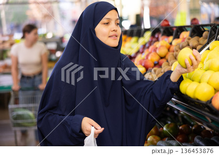 Woman in paranja shopping and choosing local juicy apples in hypermarket 136453876