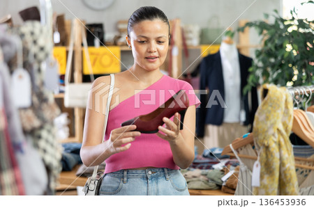 Asian woman customer turn over and choose high heels shoes in store 136453936