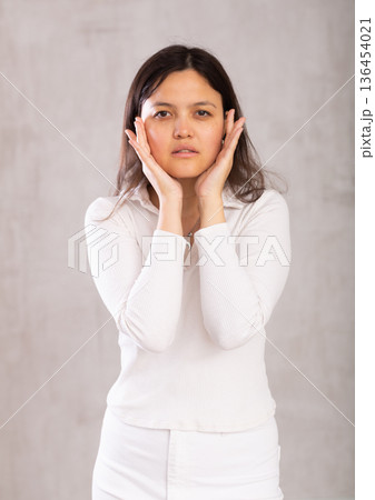Studio portrait of pretty young Asian girl in a white trouser suit on gray background Studio portrait of pretty young Asian girl in a white trouser suit on gray background 136454021