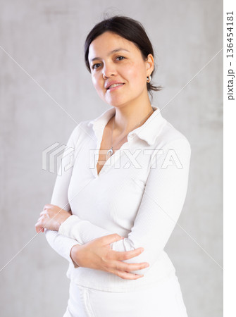 Young slender woman in light casual clothes poses with arms crossed on chest. Young slender woman in light casual clothes poses with arms crossed on chest. 136454181
