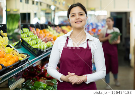 Young woman seller in uniform posing in grocery store 136454188