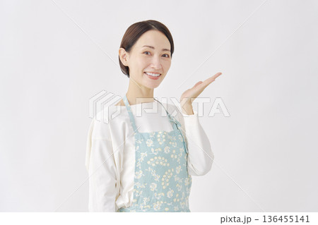 右側を手のひらで指すエプロンをつけた女性 白背景 右側を手のひらで指すエプロンをつけた女性 白背景 136455141
