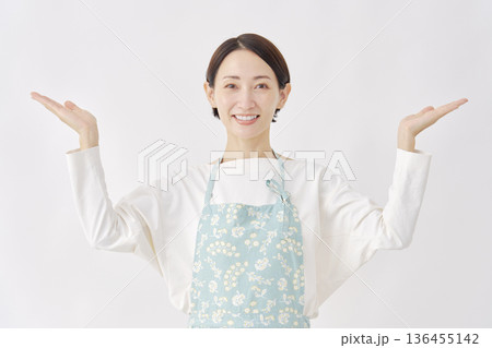 左右を手のひらで指すエプロンをつけた女性　白背景 136455142