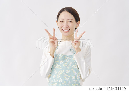 エプロンをつけた女性　ピースサイン　白背景 136455149