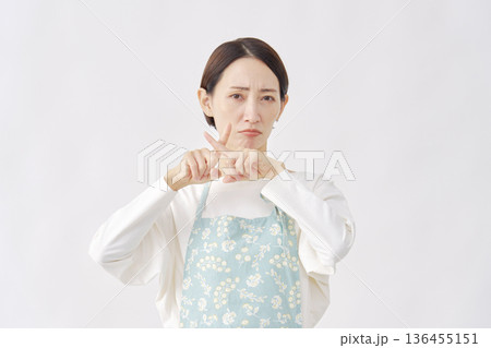 エプロンをつけた女性　ばつ印のジェスチャー　白背景 136455151