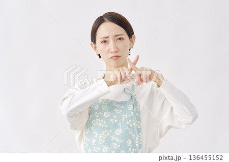 エプロンをつけた女性　ばつ印のジェスチャー　白背景 136455152