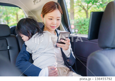 子供と一緒にタクシーに乗る忙しいお母さん 子供と一緒にタクシーに乗る忙しいお母さん 136455792