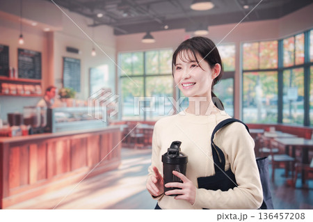 マイカップを持ってカフェに入る若い女性 136457208