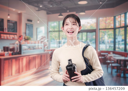 マイカップを持ってカフェに入る若い女性 136457209