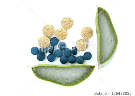 Natural health supplements including spirulina tablets and aloe vera slices on white background 136458083