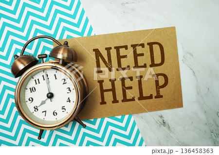 Need Help text written on paper card with alarm clock on marble background 136458363