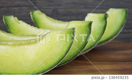close up of a green cantaloupe slice on a piece of wooden. close up of a green cantaloupe slice on a piece of wooden. 136459235