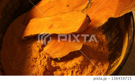 Turmeric powder and turmeric rhizomes in a bowl 136459715