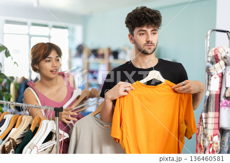 Young couple choosing dress and t-shirt in clothing store Young couple choosing dress and t-shirt in clothing store 136460581