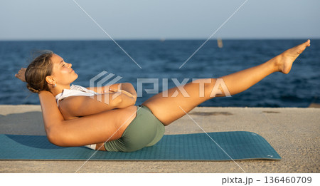 Pawanmuktasana yoga pose performed by girl on seashore Pawanmuktasana yoga pose performed by girl on seashore 136460709