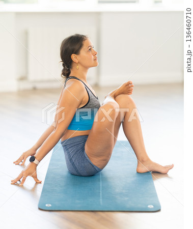 Sportive girl practicing seated pose of yoga in light room 136460710