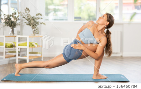 Sportive girl practicing lizard pose of yoga in light room 136460784
