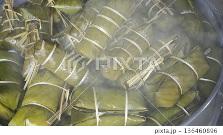 Sticky rice with coconut and banana filling, wrapped in banana leaves, cooked and steamed. Sticky rice with coconut and banana filling, wrapped in banana leaves, cooked and steamed. 136460896
