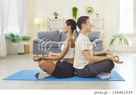 Couple meditating back to back at home on yoga mat in mindfulness together 136461334