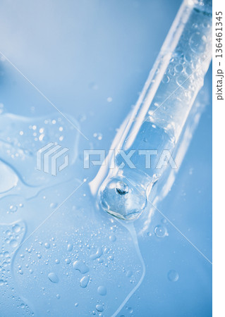 Pipette releasing transparent liquid with bubbles, splashing on light blue surface Pipette releasing transparent liquid with bubbles, splashing on light blue surface 136461345