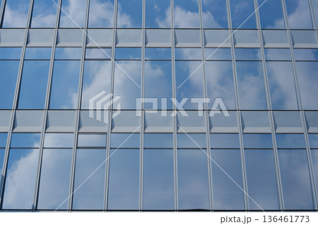 青空と雲を反射する近代的なオフィスビルのガラスファサード 136461773