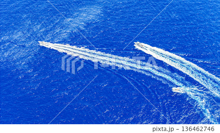 Two motorboats glide through vibrant blue waters, leaving behind trails of white foam on a sunlit day in a coastal paradise Two motorboats glide through vibrant blue waters, leaving behind trails of white foam on a sunlit day in a coastal paradise 136462746