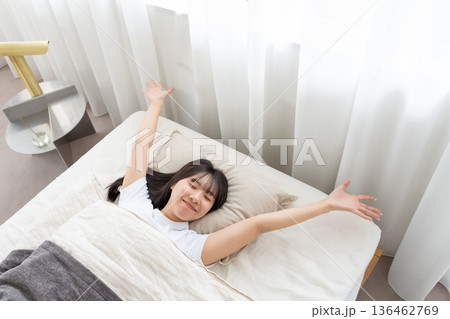 ベッドで伸びをする女性 136462769