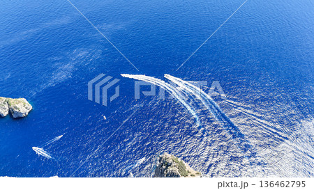 Boats gliding gracefully over vibrant blue waters near stunning rocky coastlines at midday Boats gliding gracefully over vibrant blue waters near stunning rocky coastlines at midday 136462795