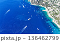 Vibrant boats glide across turquoise waters near a rocky coastline under bright sunshine in a coastal paradise 136462799