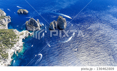 Breathtaking view of azure waters and rocky formations near a coastal paradise filled with boats sailing beneath a clear sky Breathtaking view of azure waters and rocky formations near a coastal paradise filled with boats sailing beneath a clear sky 136462809