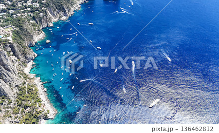 Vibrant blue waters of Capri invite exploration by boats under the sun in a stunning coastal landscape 136462812