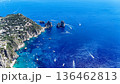 Breathtaking azure waters surround the stunning Faraglioni rocks in Capri during a vibrant summer day filled with boats 136462813