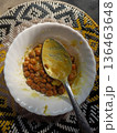 Authentic Indian Black Chickpea Curry (Kala Chana Masala) in a White Bowl with Spoon on a Woven Mat Background. 136463648