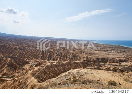 Aksai Canyon panorama with vast eroded landscape near calm water. Natural geological formation in Kyrgyzstan for nature tourism. Aksai Canyon panorama with vast eroded landscape near calm water. Natural geological formation in Kyrgyzstan for nature tourism. 136464217