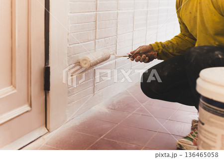 Man painting a house wall with roller in white color. Man painting a house wall with roller in white color. 136465058