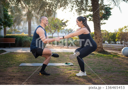 Pregnant Woman and Partner Do Outdoor Partner Squat Exercise in Park for Fitness Together 136465453