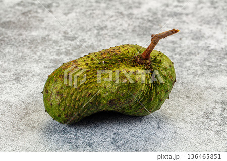 One whole raw soursop fruit, or graviola, isolated on a textured background. One whole raw soursop fruit, or graviola, isolated on a textured background. 136465851