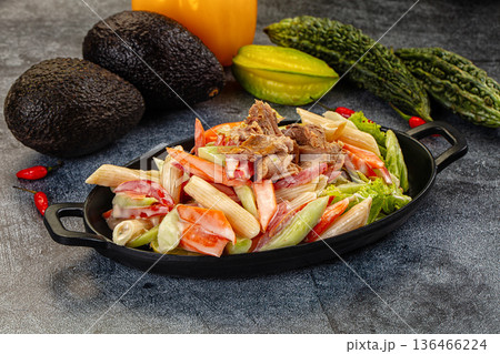 Hearty pasta salad with tuna and fresh vegetables on a dark, textured surface 136466224
