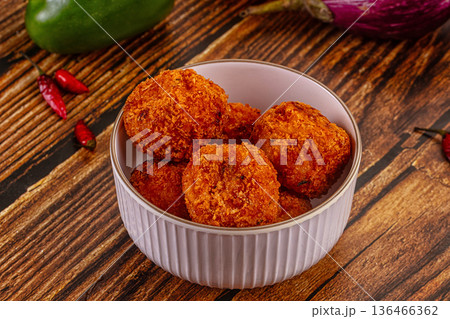 Golden fried cheese and vegetable balls, appetizer dish with fresh chili, peppers, and carrots on a wood table. Golden fried cheese and vegetable balls, appetizer dish with fresh chili, peppers, and carrots on a wood table. 136466362